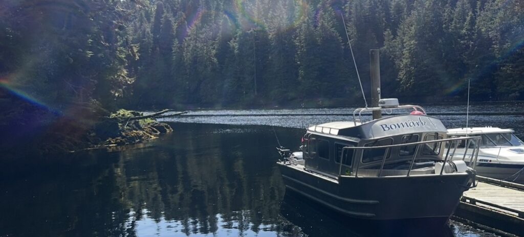 The Bomark J, a 32-foot custom Glacier Craft fishing boat, resting on the calm, scenic waters of Ketchikan, Alaska surrounded by evergreen trees.
