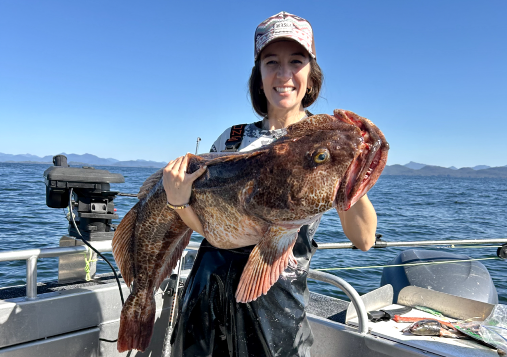 A happy guest holding a massive trophy fish on the deck of a boat during an Alaska Ocean Safaris Ketchikan fishing charter.